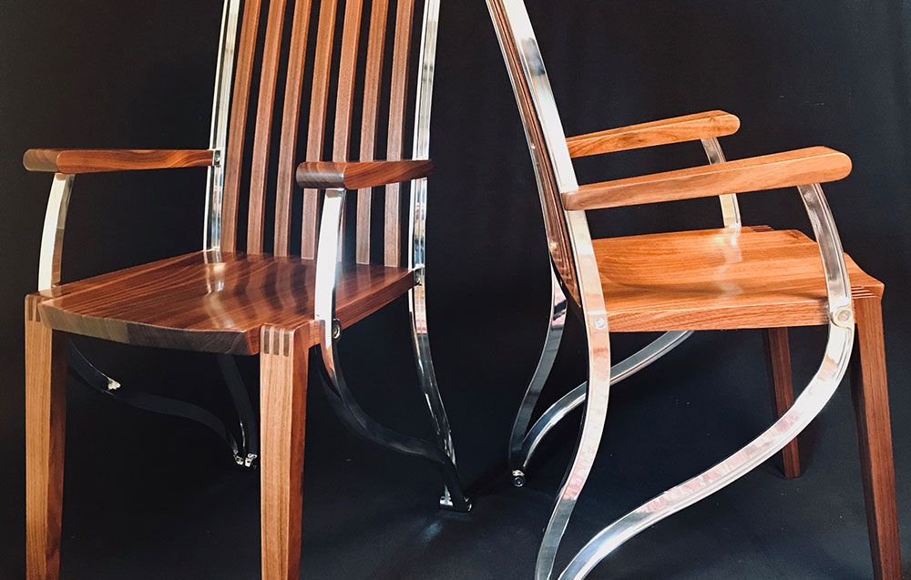 Two contemporary wooden chairs are sitting next to each other on a black surface.