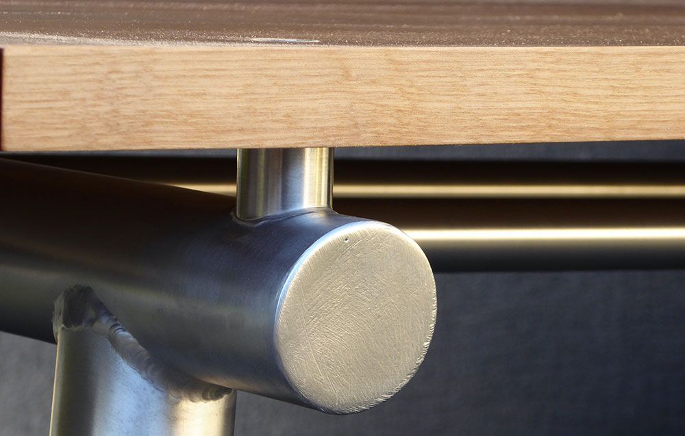 A metal pipe is attached to a wooden table