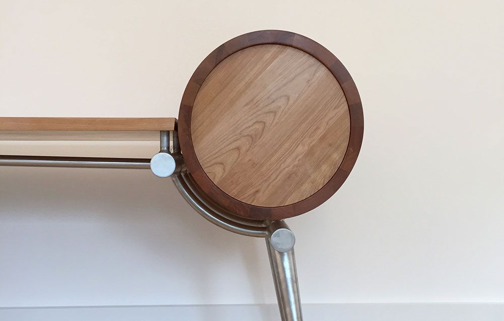 A modern designer wooden table with a metal frame and a round wooden top