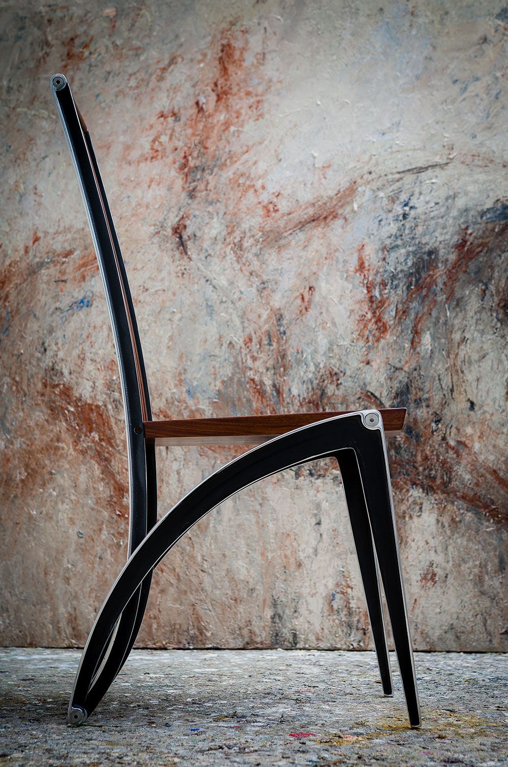A black walnut chair is sitting in front of a wall.
