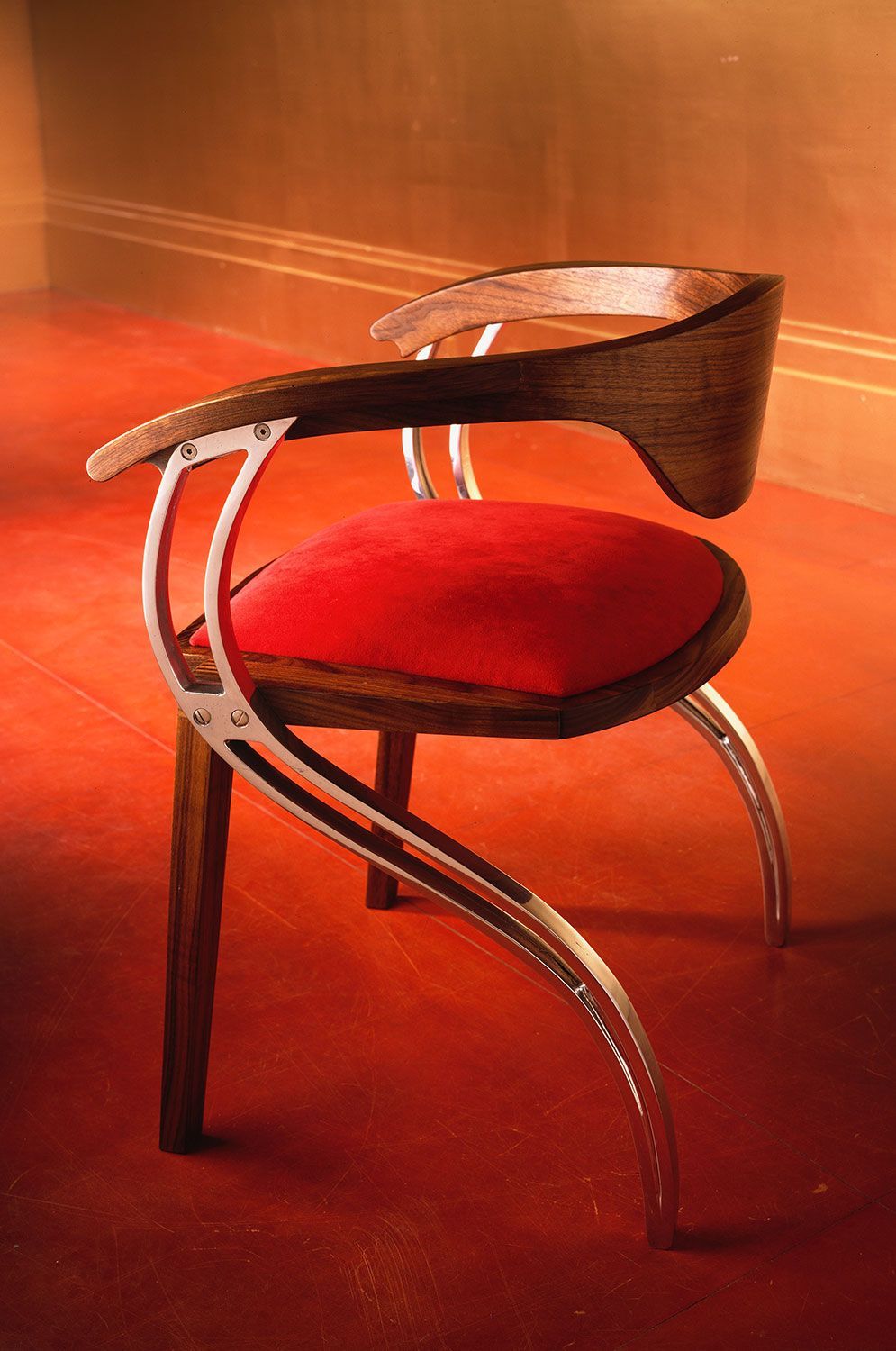 A custom designed and crafted dining chair with a red cushion is sitting on a red carpet