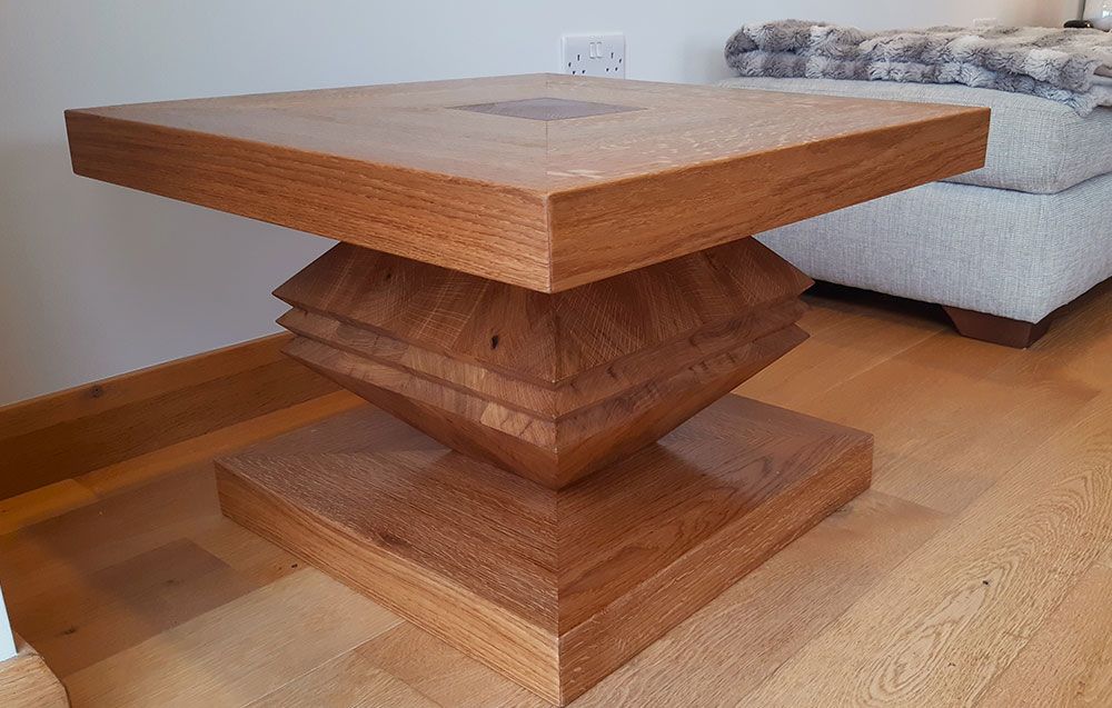 The tailored oak Itzamná coffee table is sitting on a wooden floor next to a couch.