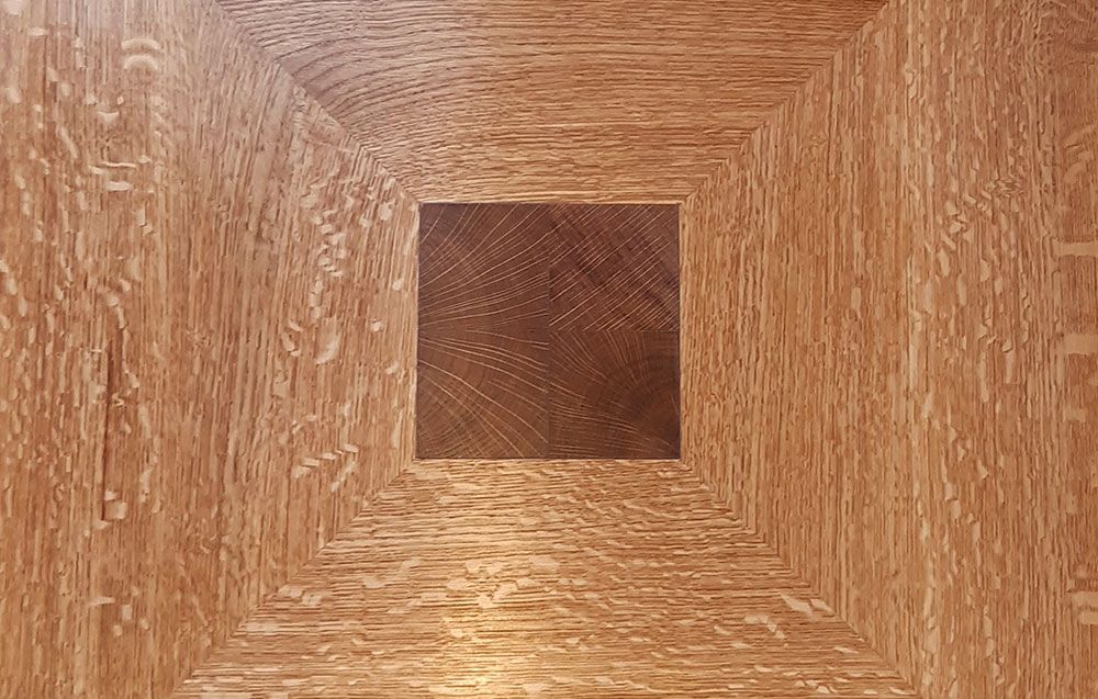 A close up of a piece of handmade woodwork with a square in the middle.
