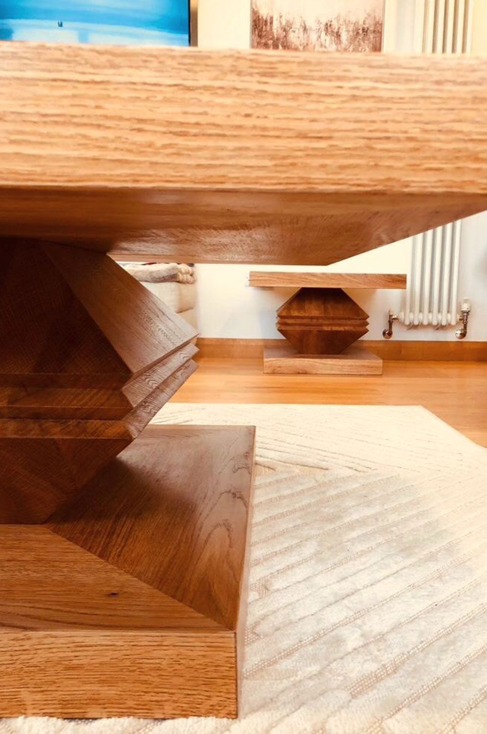 A wooden table wood works of art is sitting on a white rug in a living room.