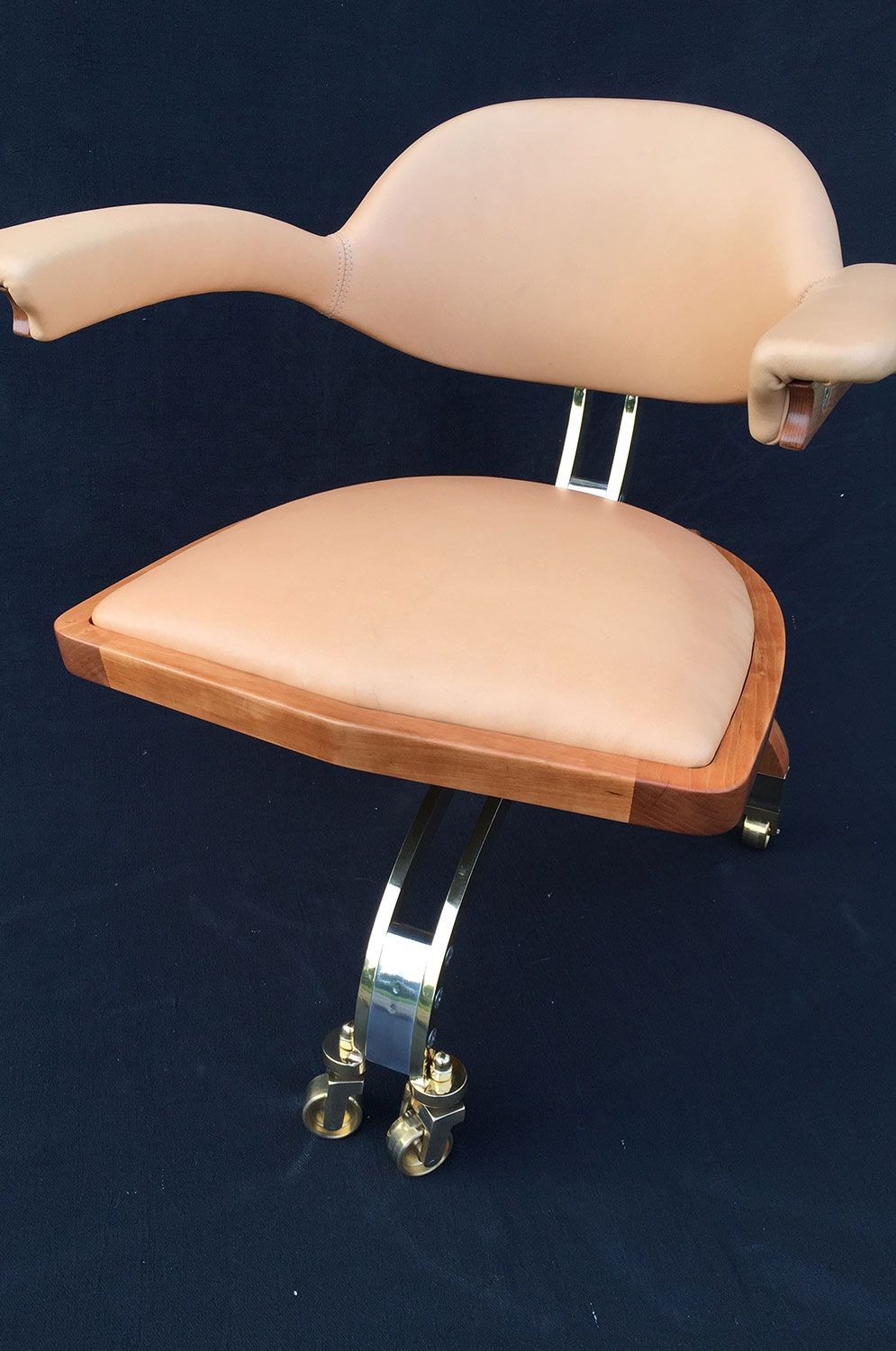 A office chair with a wooden frame and a tan seat designed and crafted by sebastian blakeley