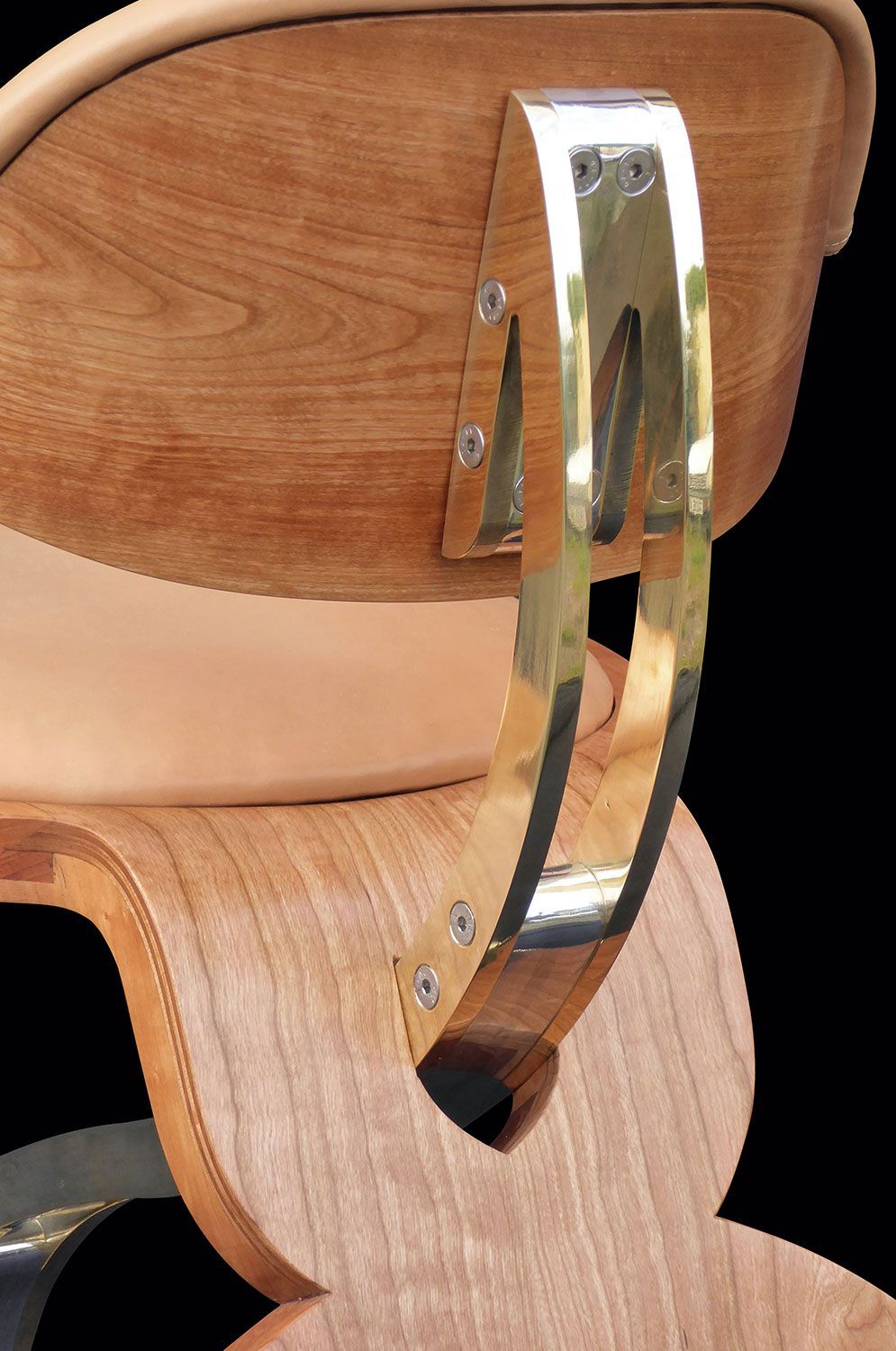 A close up of a hand crafted wooden chair with a metal arm rest built by sebastian blakeley