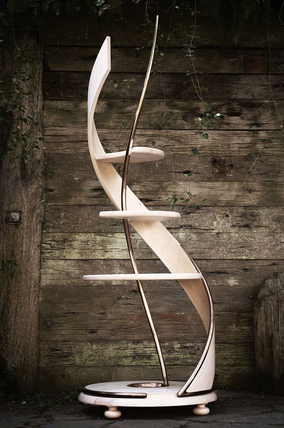 A wooden handcrafted shelf is sitting in front of a wooden wall.