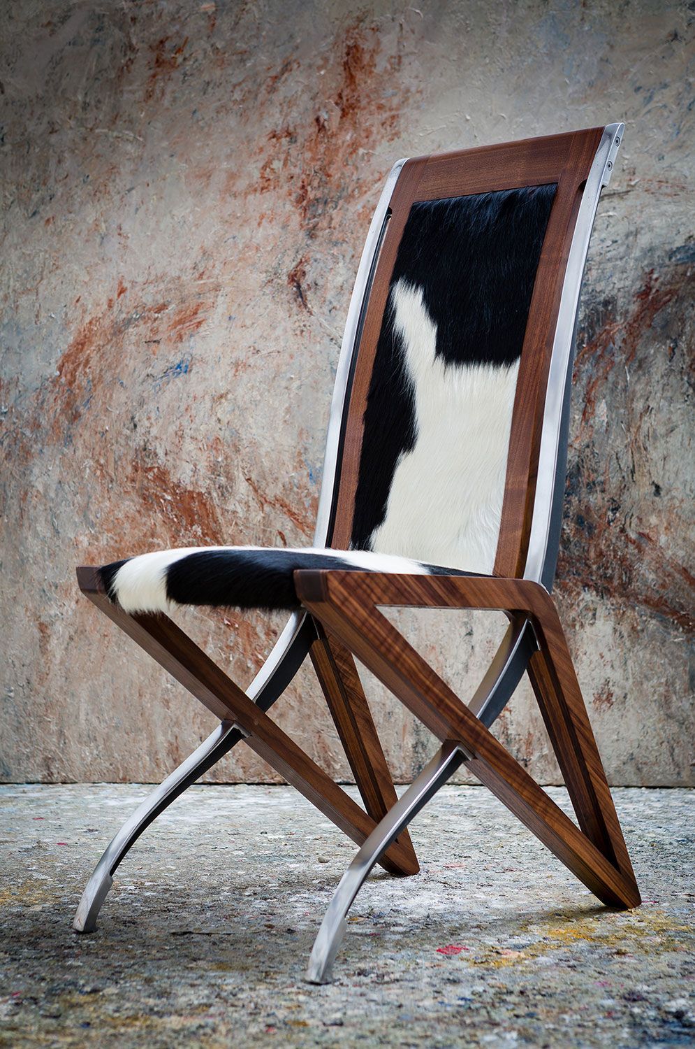A hand crafted designer wooden chair with a black and white cowhide seat