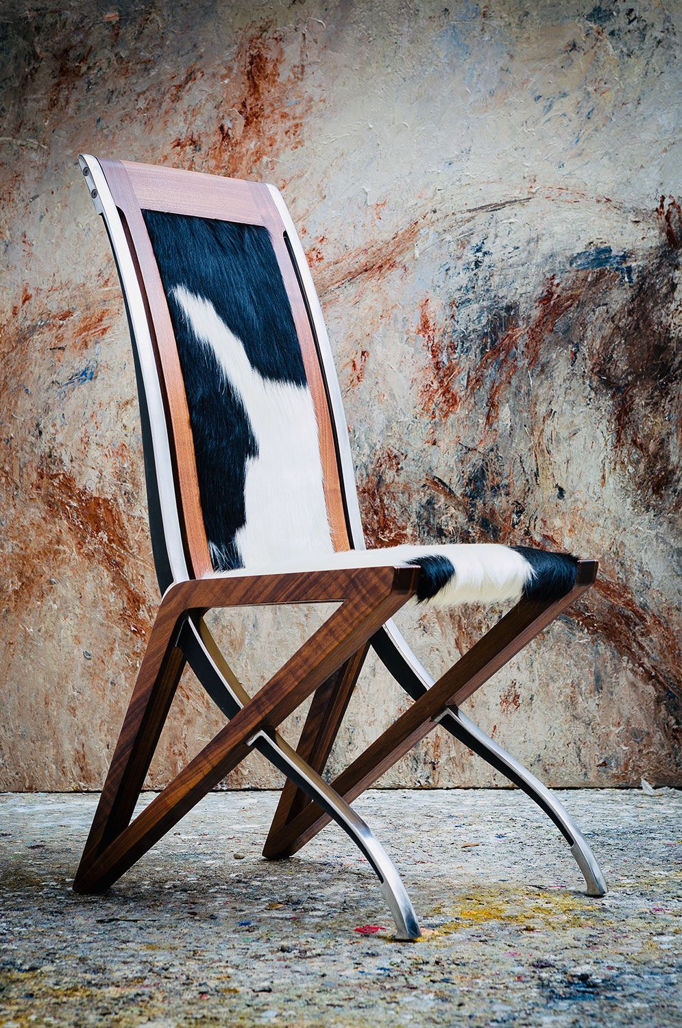 A custom made chair with a cowhide seat and back is sitting in front of a wall.
