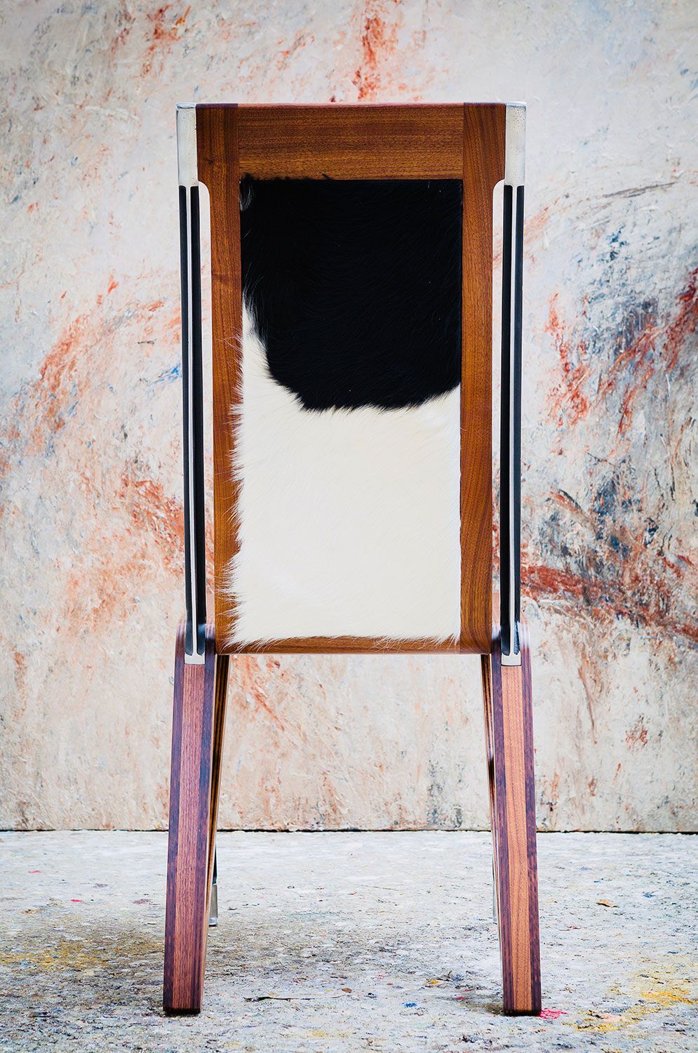 A custom built wooden chair with a black and white cowhide seat