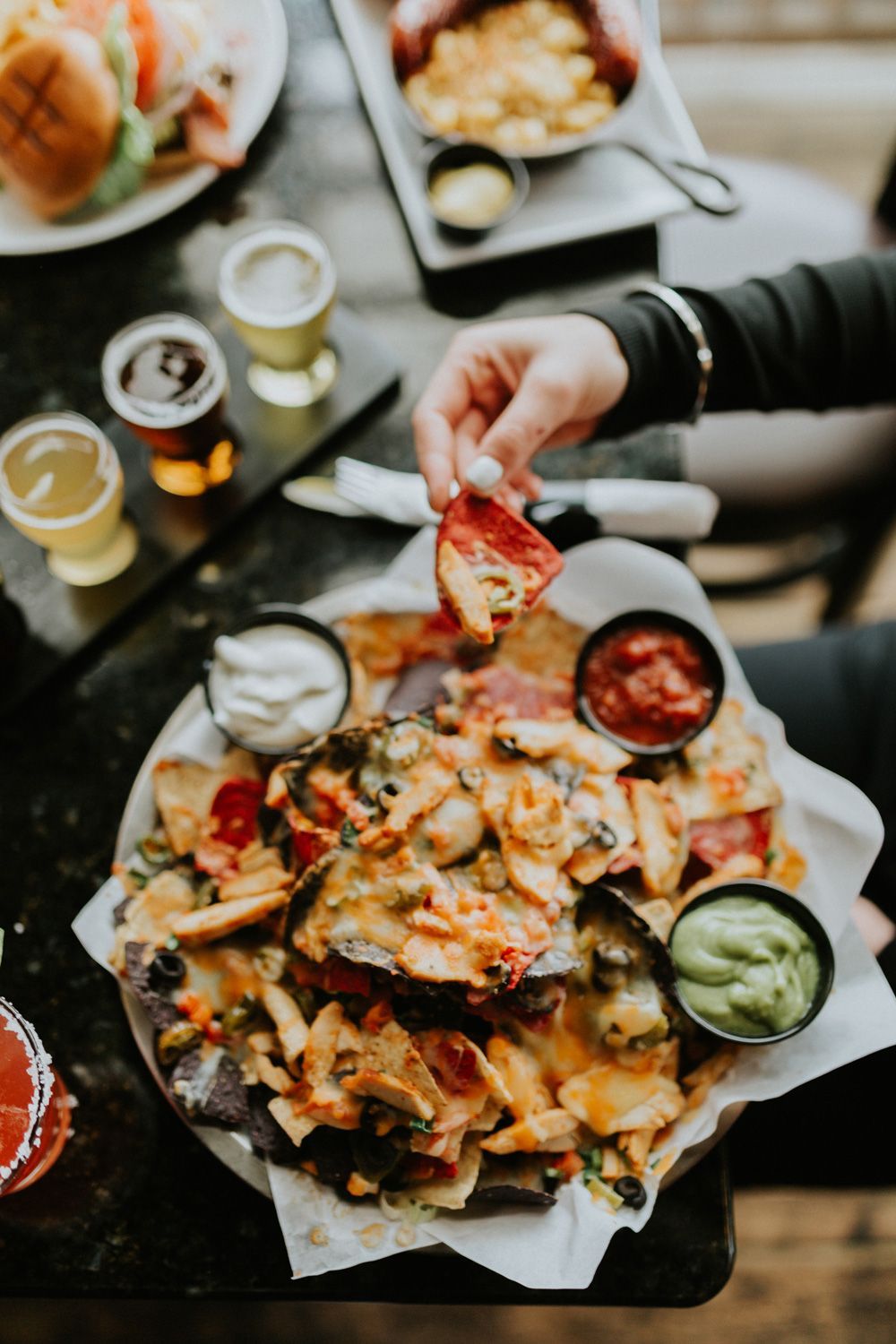 A person is dipping a tortilla chip into a bowl of nachos.