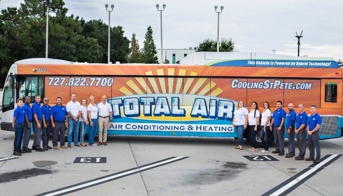 Group of people in blue and white shirts in front of a bus with 