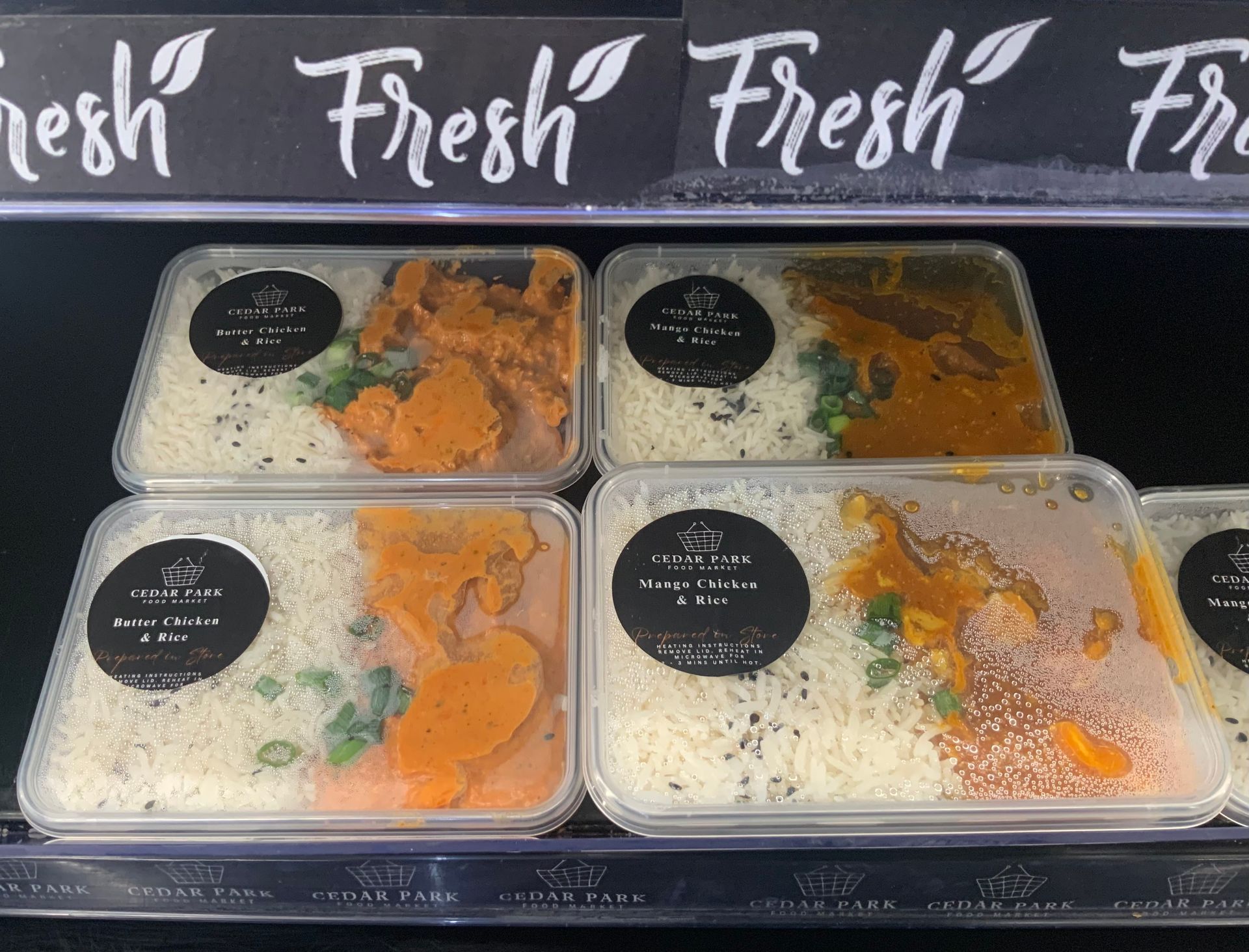 Four packaged rice meals with orange curry and greens — Cedar Park Supermarket In Taranganba, QLD