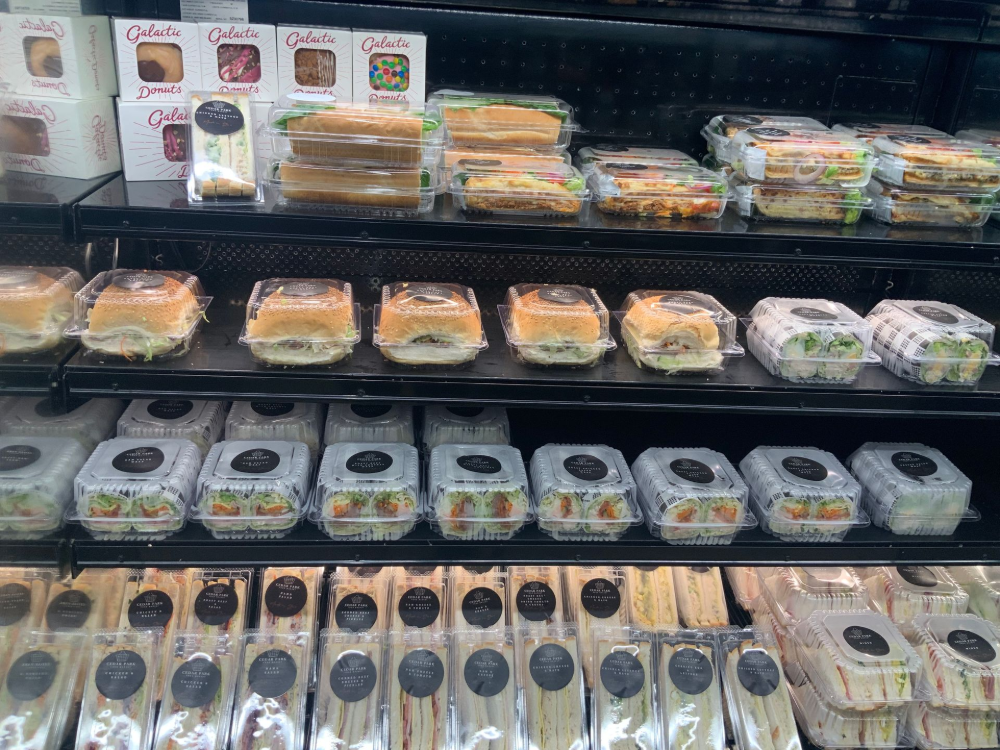 Refrigerated grocery shelf stocked with packaged sandwiches, salads, and snack trays — Cedar Park Supermarket In Taranganba, QLD