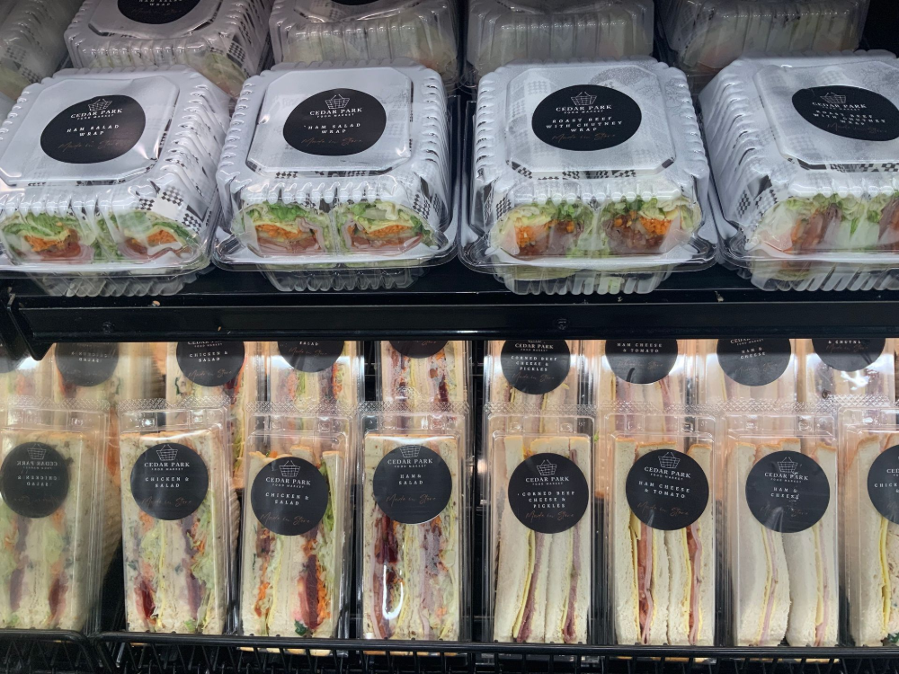 Refrigerated shelf with packaged salads and wrap sandwiches in clear plastic containers— Cedar Park Supermarket In Taranganba, QLD