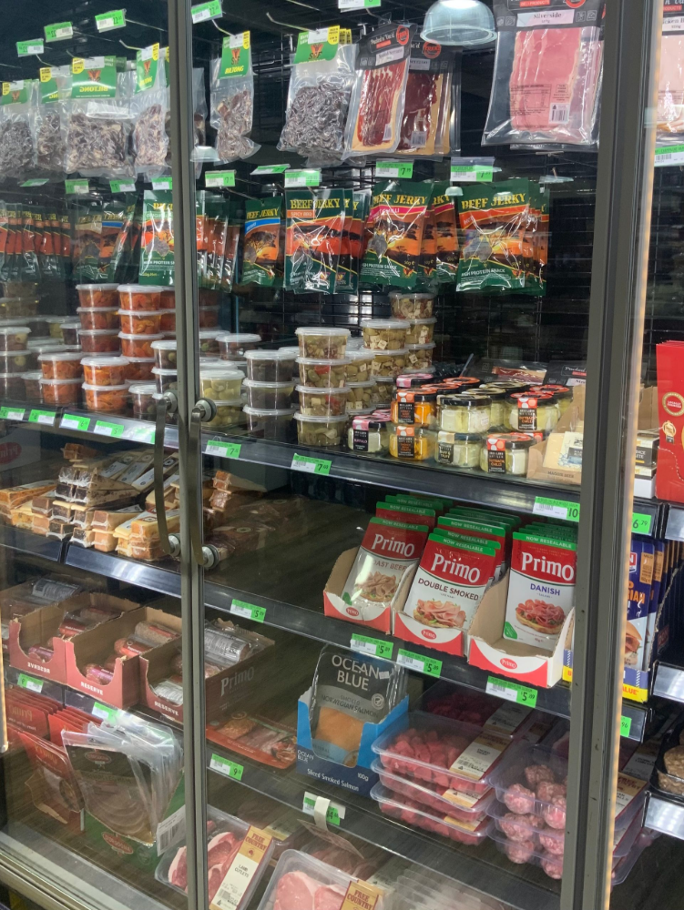 Store display case filled with packaged snacks, dips, and desserts on glass shelves— Cedar Park Supermarket In Taranganba, QLD