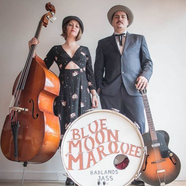 A man and woman standing next to a drum that says blue moon marqee