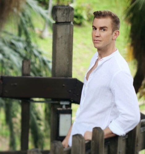 A man in a white shirt is leaning on a wooden fence