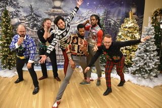 A group of men are posing for a picture in front of a christmas tree.