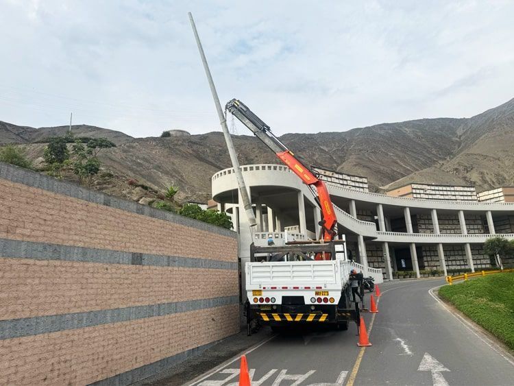 Un camión con una grúa en la parte trasera circula por una carretera.