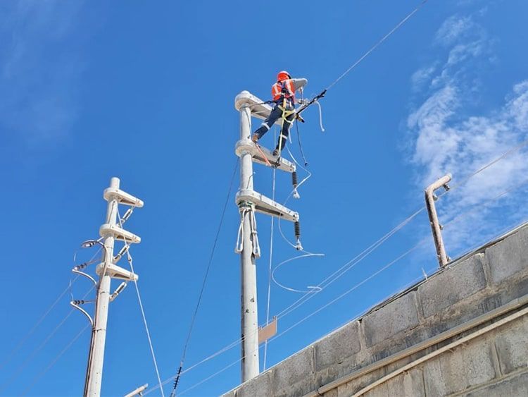 Un hombre está trabajando en una línea eléctrica en la parte superior de un edificio.