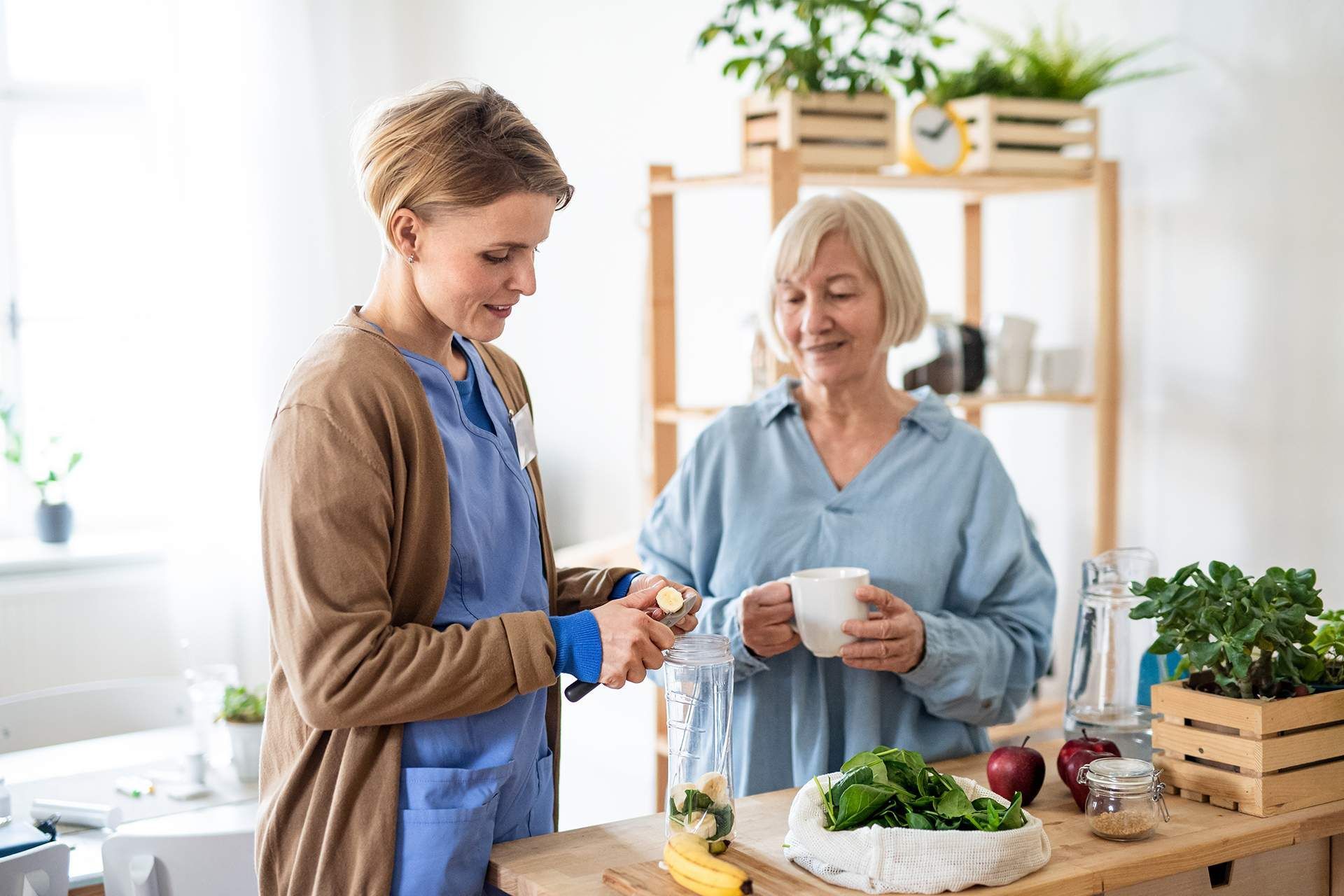 Two people preparing food together in a bright kitchen, smiling beside fresh vegetables and utensils