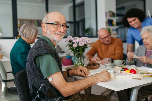 Seniors sharing tea and cake at a table in a bright community room