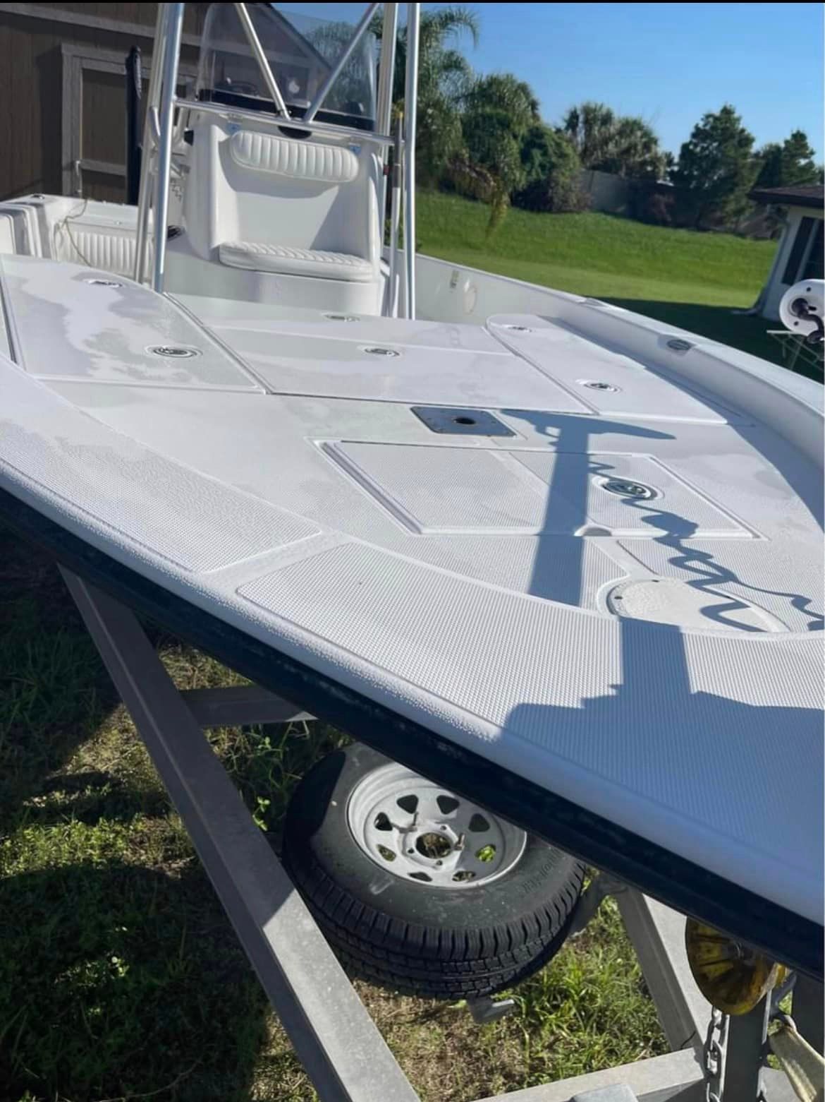 White fishing boat on a trailer, sunny outdoor setting.