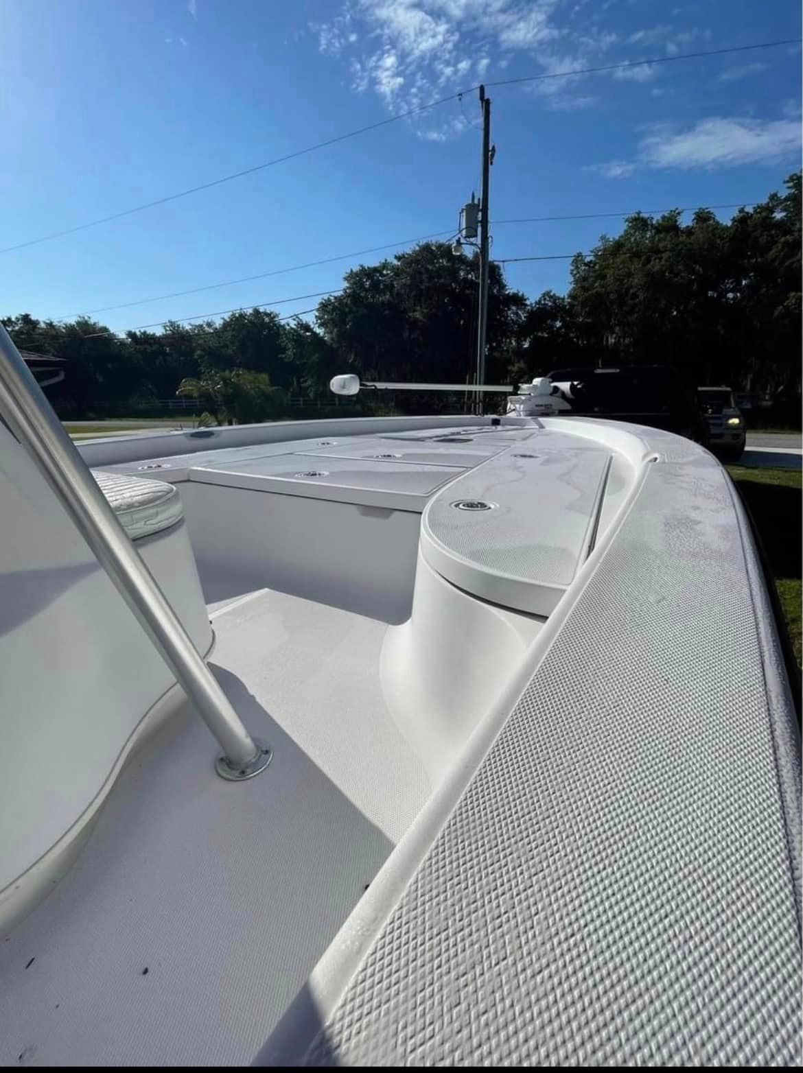 White boat deck with railing and mast, outdoors on a sunny day.