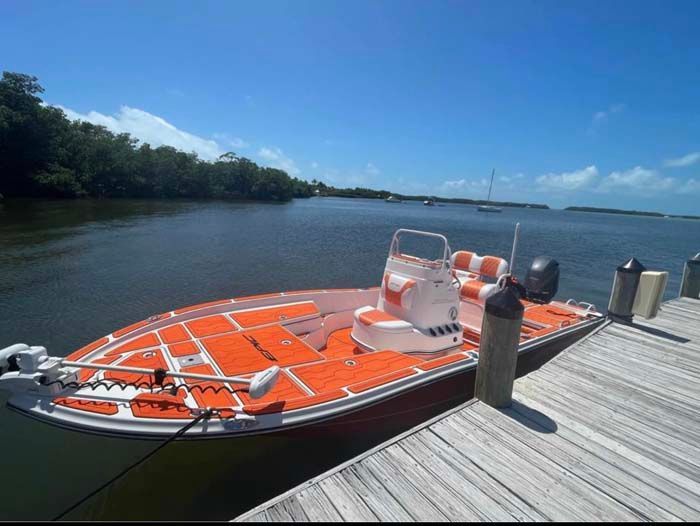 Orange and white boat docked at a wooden pier on a sunny day.