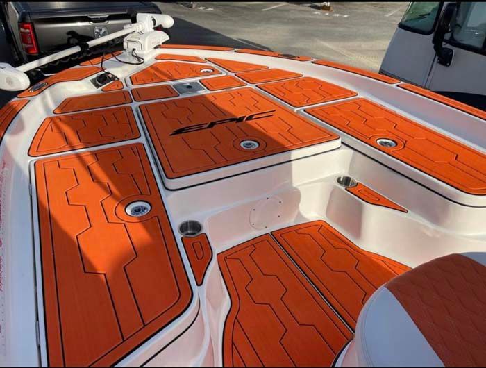 Orange and black boat decking. Close-up of a white boat with orange cushioned flooring and black outlines.