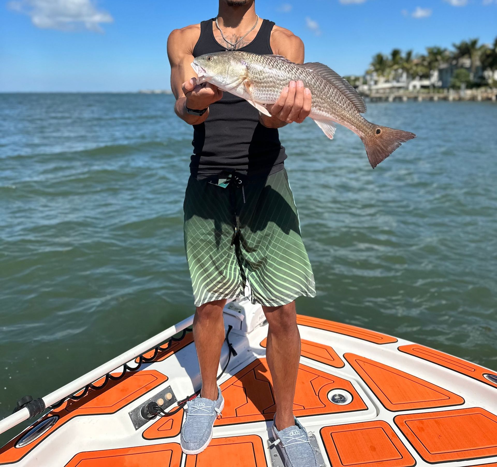 Man holding a fish on a boat; ocean background.