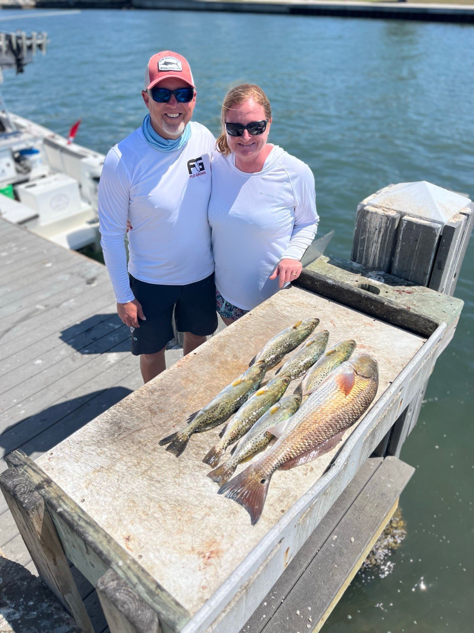 Two people stand by a dock with freshly caught fish.