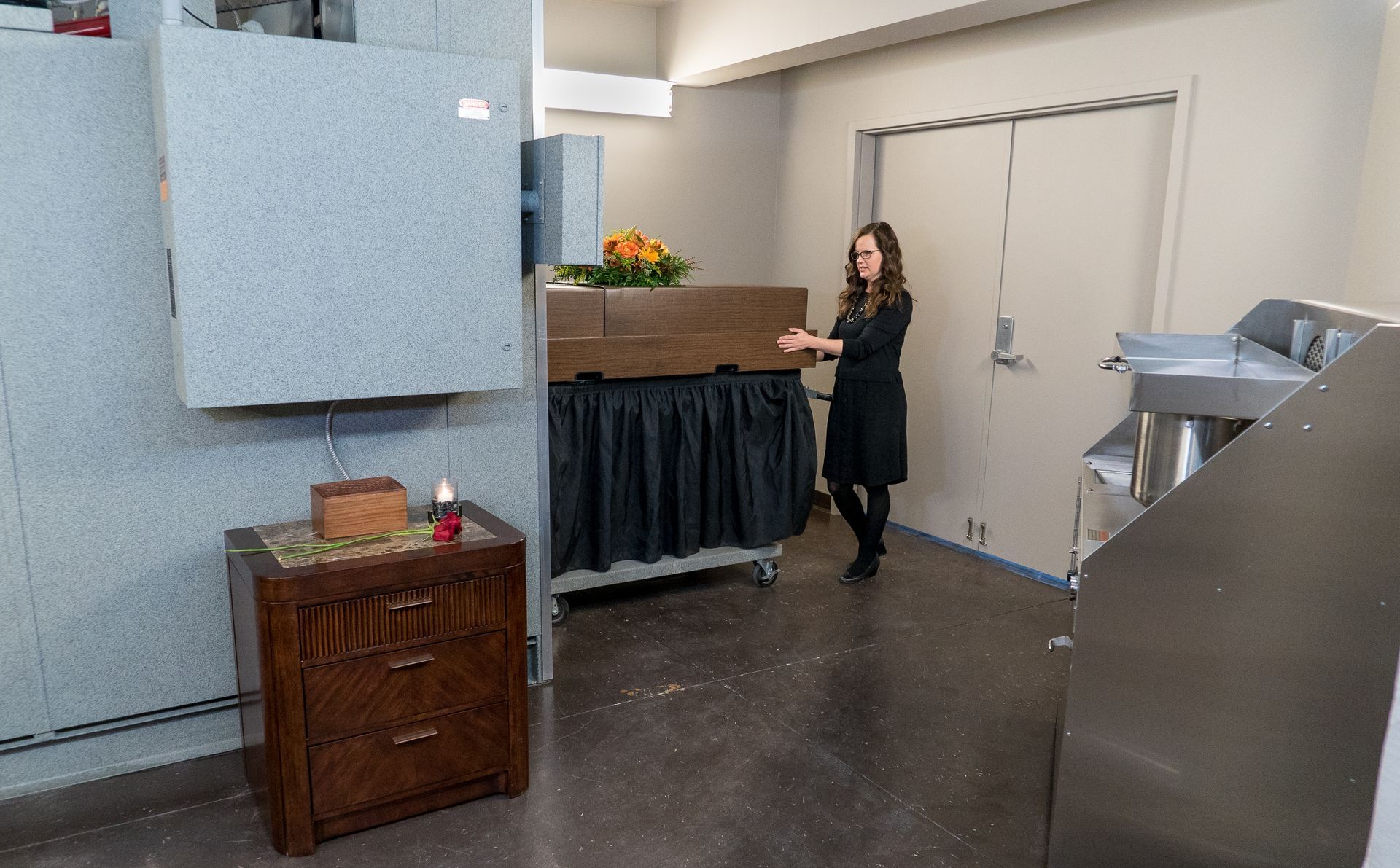 A woman is standing in a room holding a coffin.