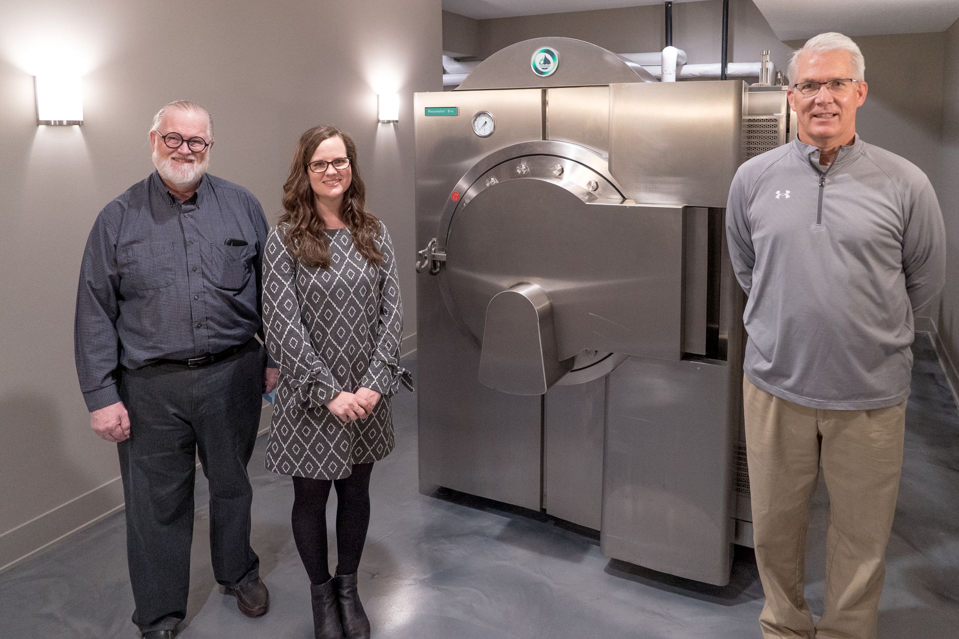 Three people are standing in front of a machine in a room.