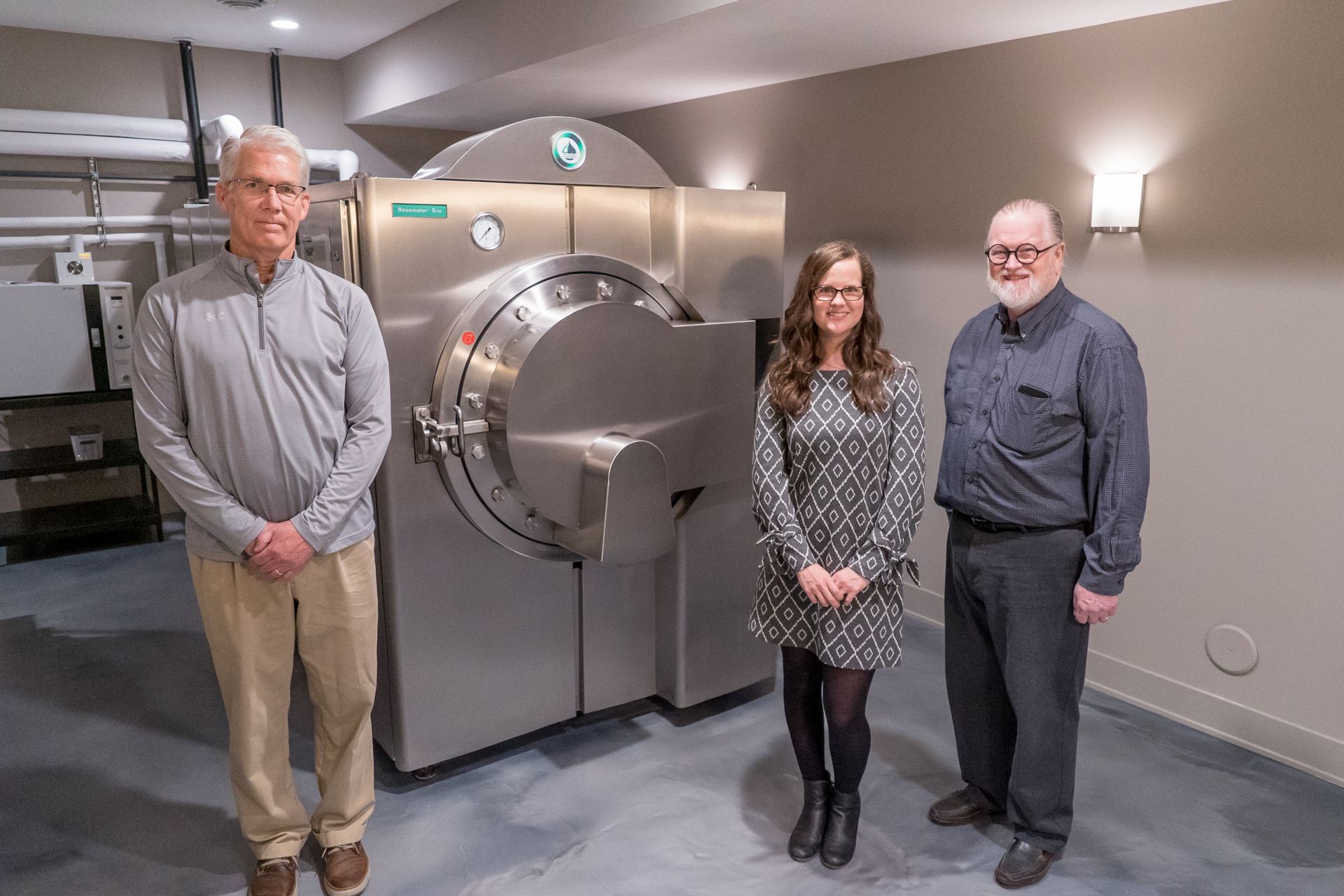 Three people are standing in front of a machine in a room.