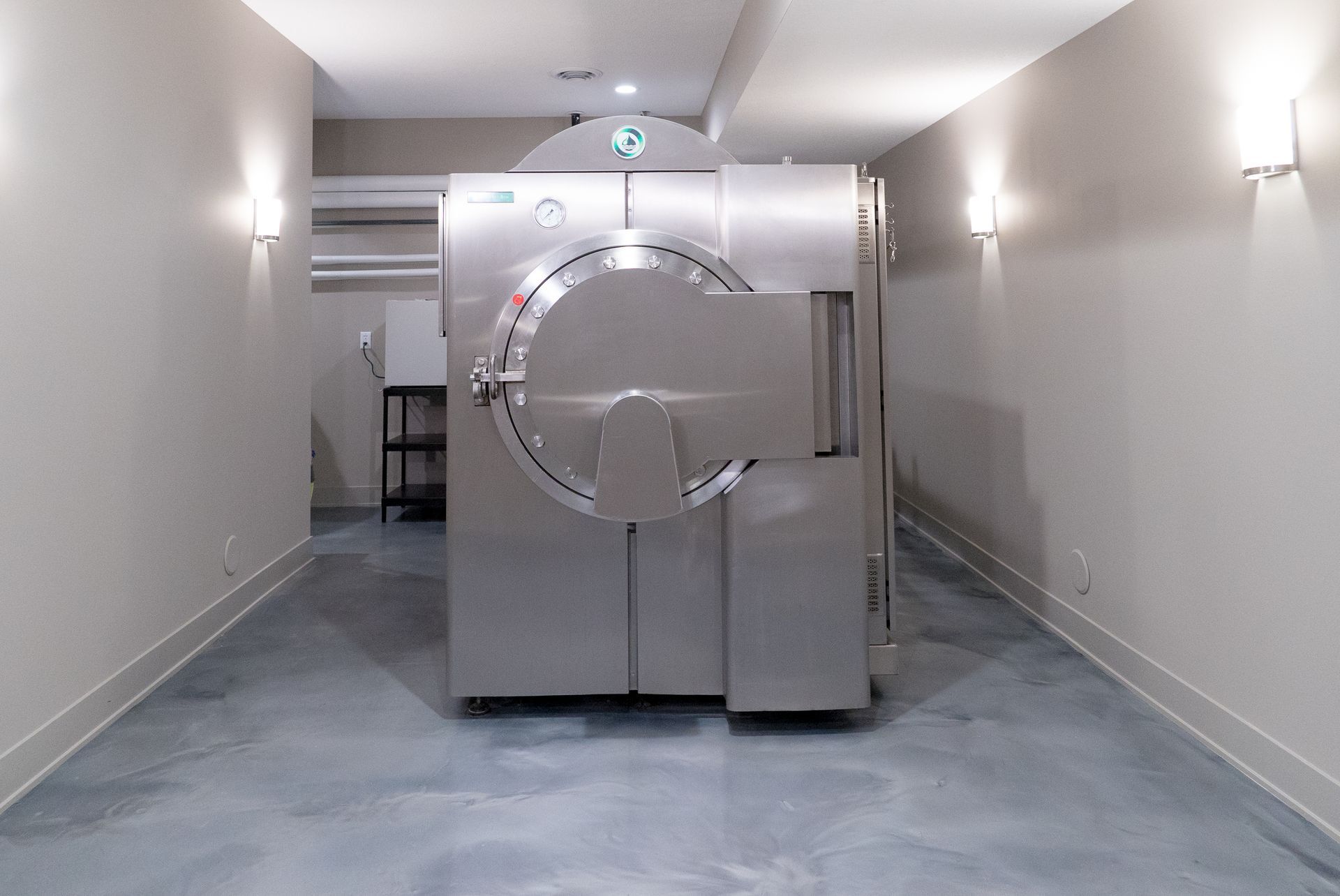 A large stainless steel machine is sitting in the middle of a hallway.