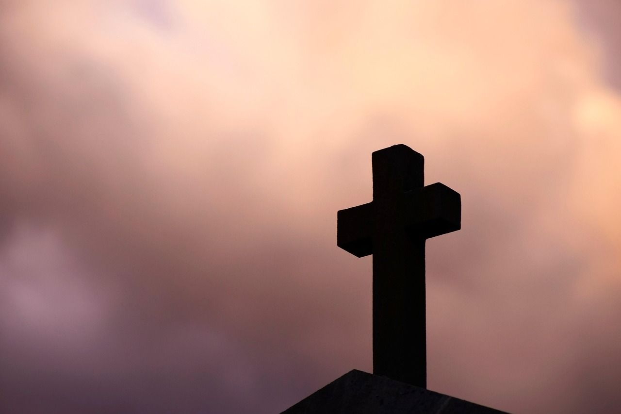 Stone cross set against a bright blue sky, representing remembrance and faith associated with cremation services Chaska, MN.