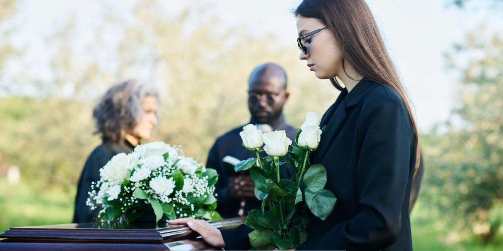 Family attending a graveside service with white roses in Chaska, MN.