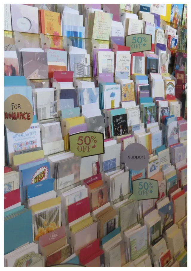 Greeting cards displayed on a store rack with signs indicating 50% off.