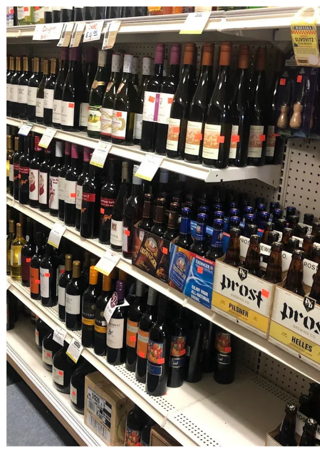 Shelves stocked with various wine and beer bottles in a store.
