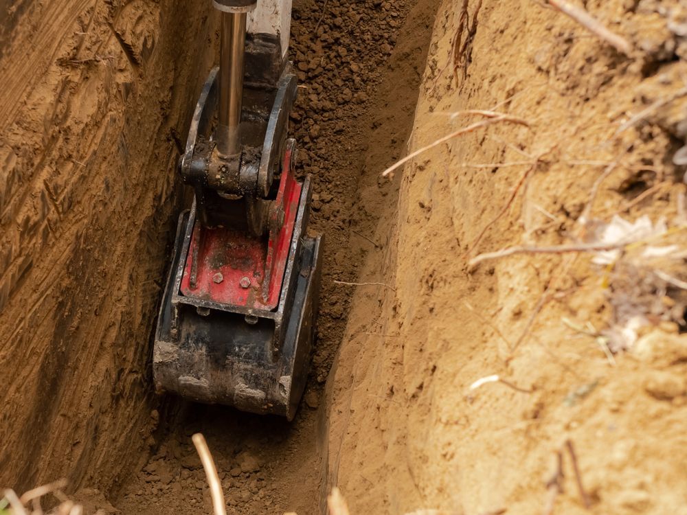 Mini Excavator Digging a Narrow Trench in Brown Soil — Bigfoot Earthmoving In Bangalow, NSW