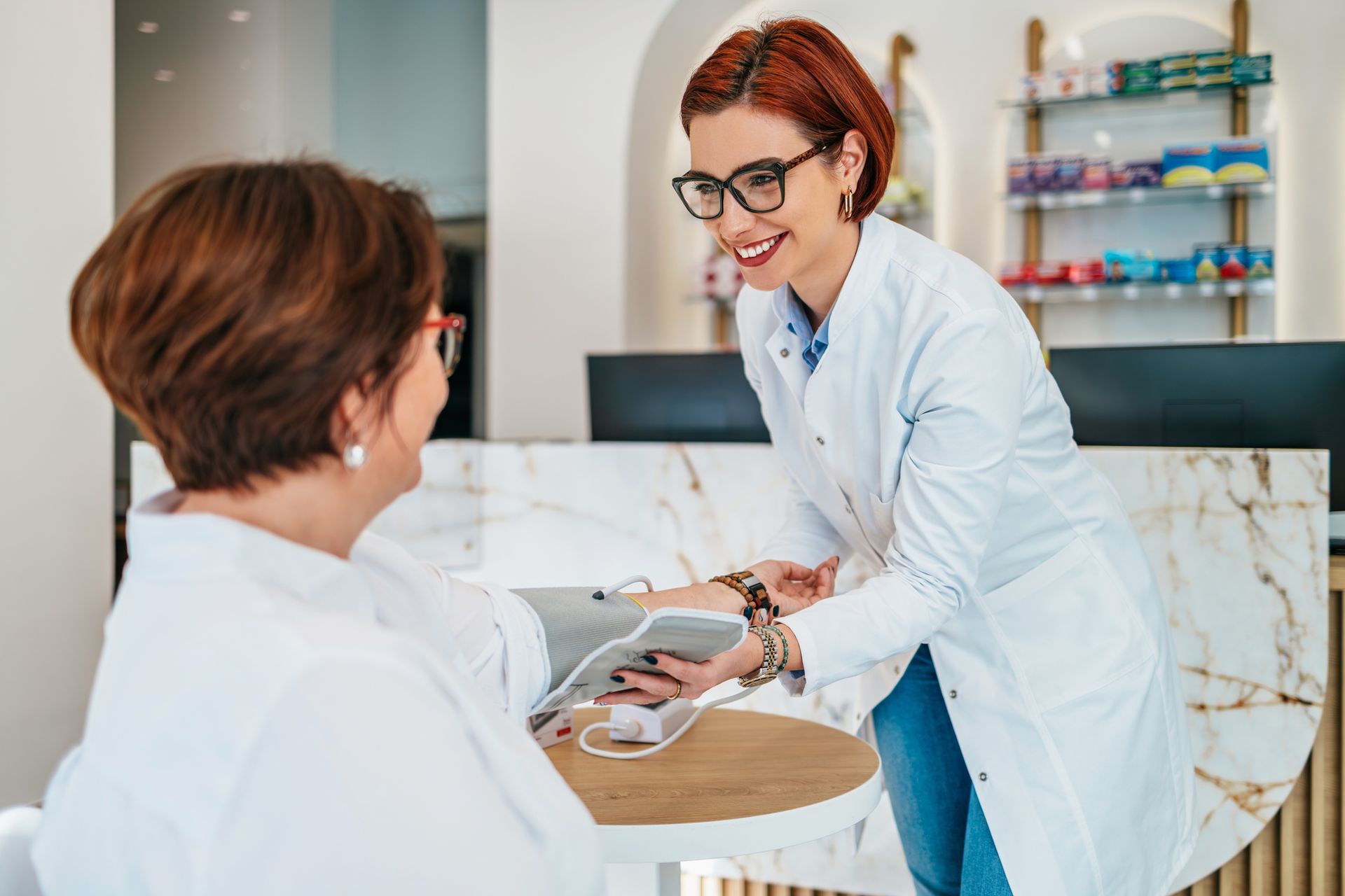 Una farmacista parla con un paziente in farmacia.