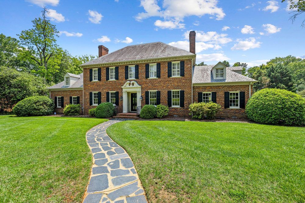 A large brick house with a stone walkway leading to it.