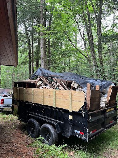 A trailer filled with wood is parked in the woods.
