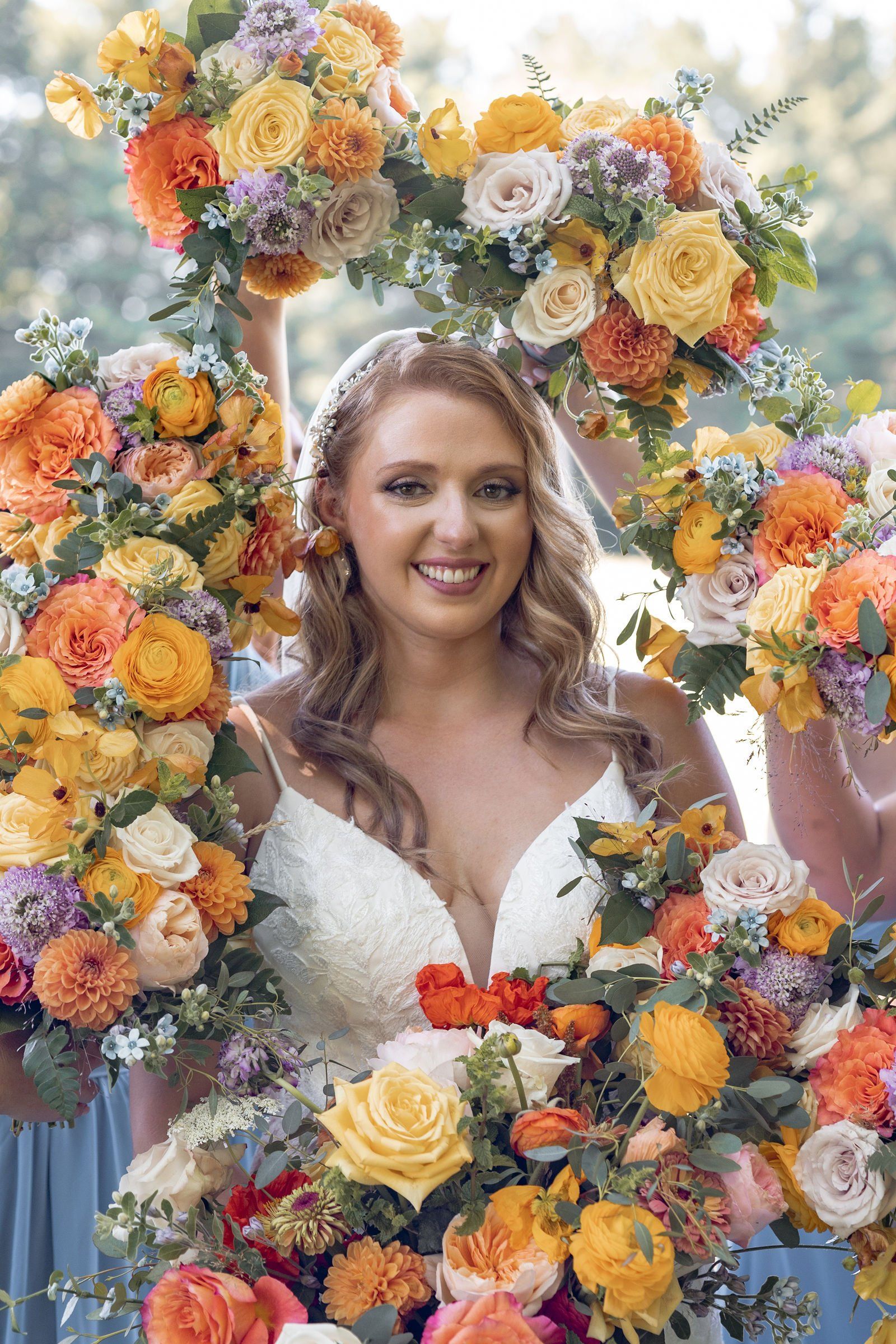 A bride and her bridesmaids are holding colorful bouquets of flowers - designed by Flowers by Leo