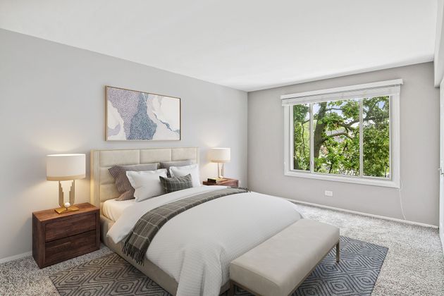 a bedroom with a bed , nightstands , lamps and a window .