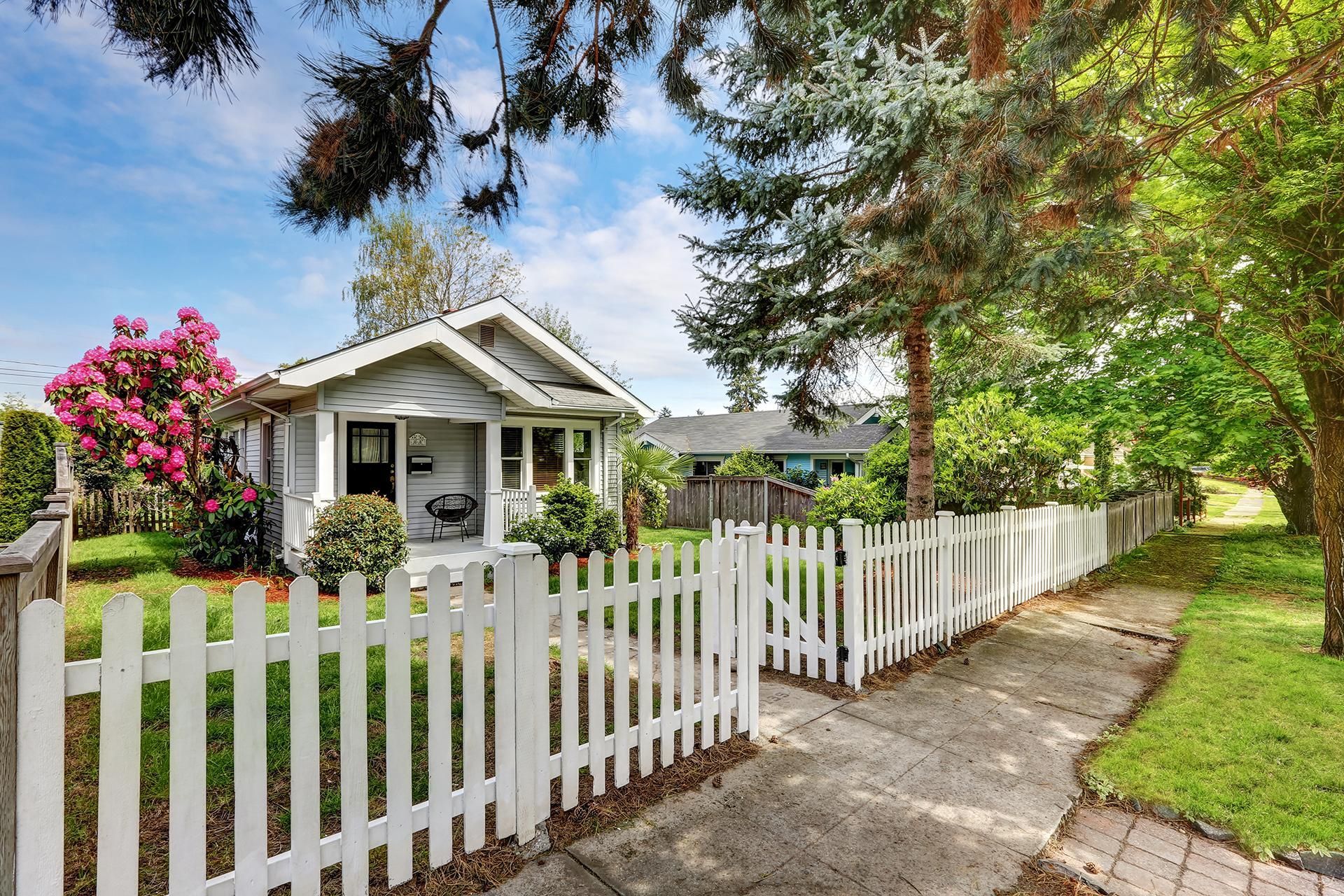 a white picket fence surrounds a small house .