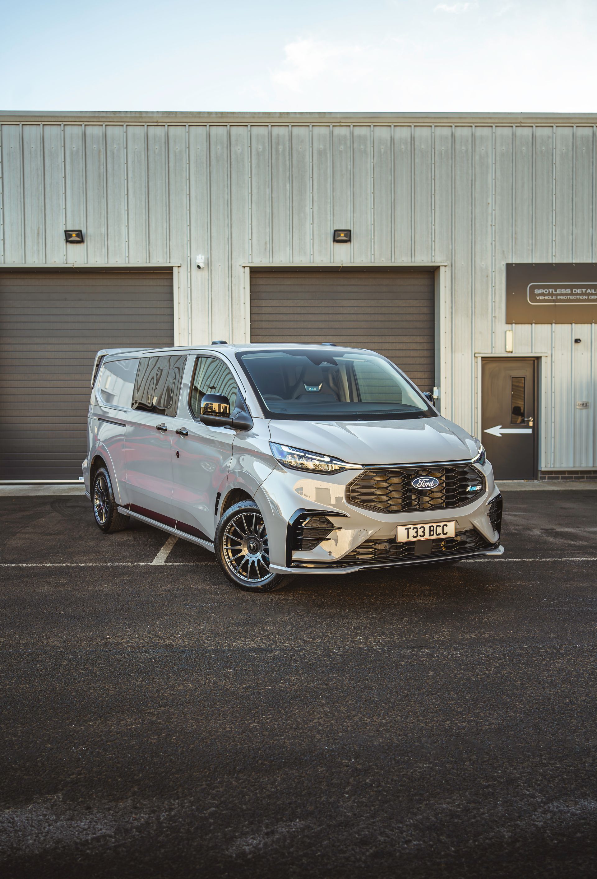 A grey van is parked in front of a building.