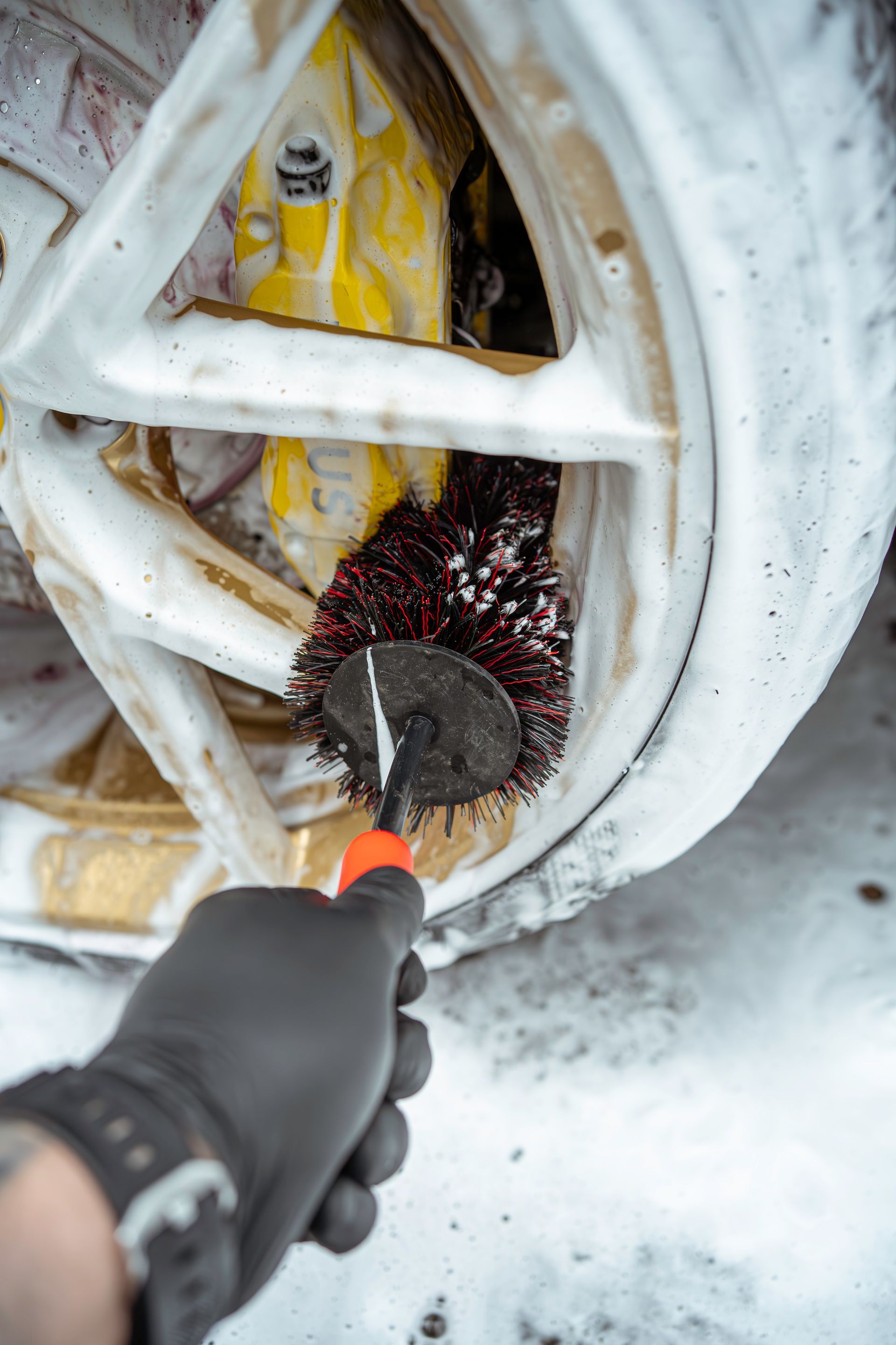 A person is cleaning a car wheel with a brush.